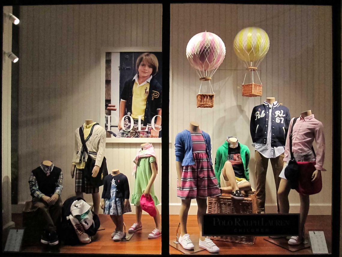 Ralph lauren window display with mannequins dressed in children clothing and balloon retail props.