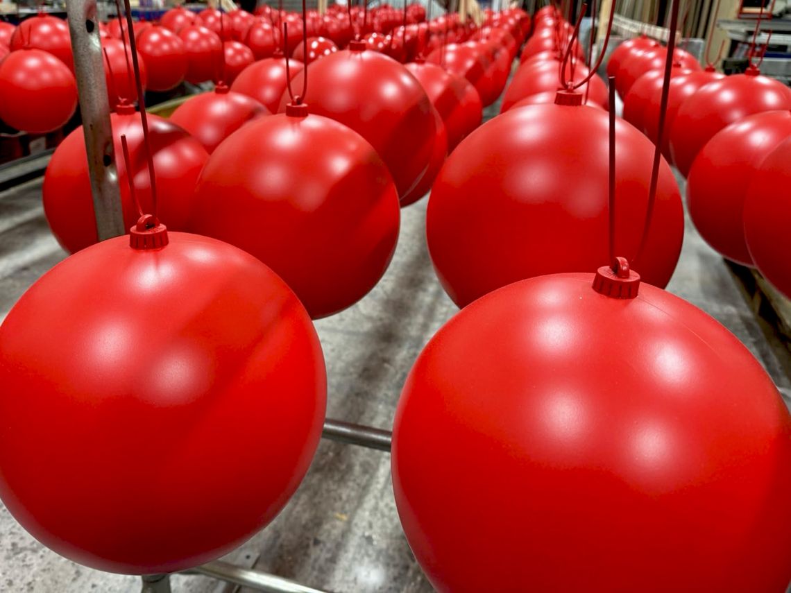 Freshly painted red baubles hanging to dry.